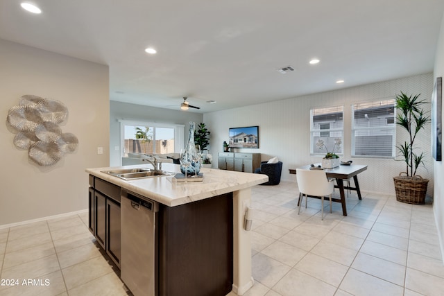 kitchen with an island with sink, sink, stainless steel dishwasher, light tile patterned floors, and dark brown cabinetry