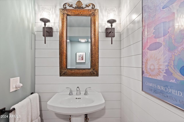 bathroom featuring wood walls and sink