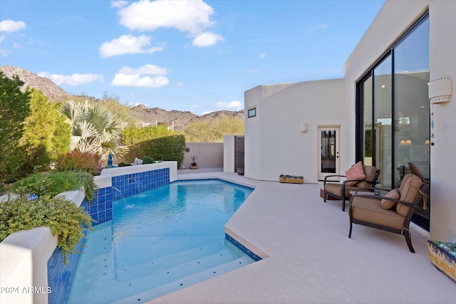 view of swimming pool with a mountain view, pool water feature, and a patio