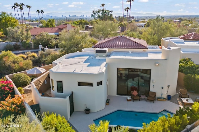 back of property with a mountain view and a patio