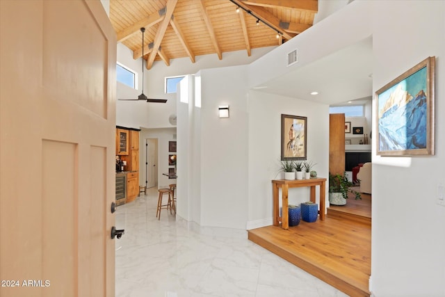 hall featuring beamed ceiling, a towering ceiling, and wood ceiling