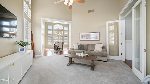 living room featuring carpet, french doors, visible vents, and a towering ceiling