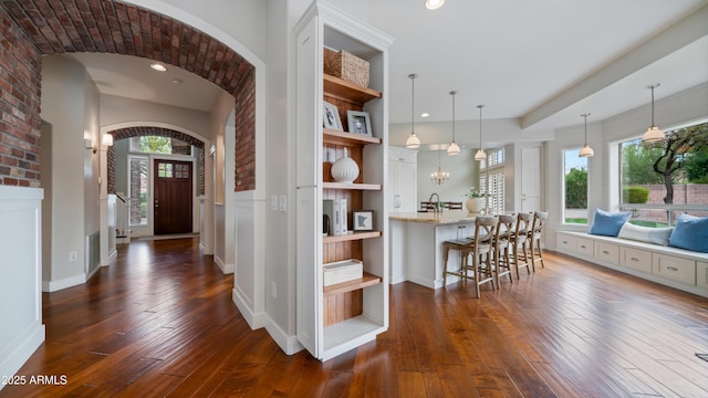 kitchen featuring open shelves, hanging light fixtures, dark wood-type flooring, white cabinets, and a kitchen breakfast bar