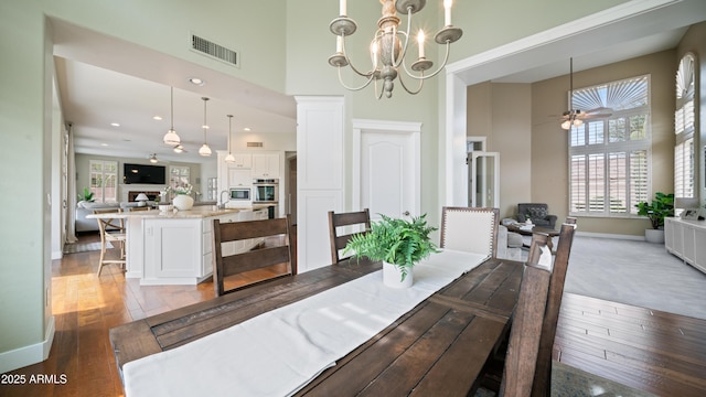 dining area featuring a high ceiling, a healthy amount of sunlight, visible vents, and wood-type flooring