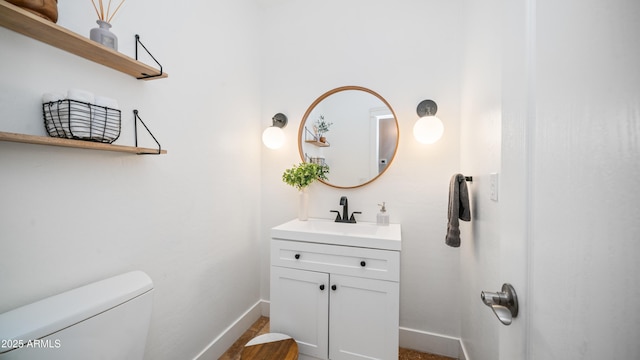 half bath with vanity, toilet, and baseboards