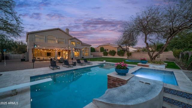 pool at dusk featuring a patio area, a fenced in pool, an in ground hot tub, and a fenced backyard