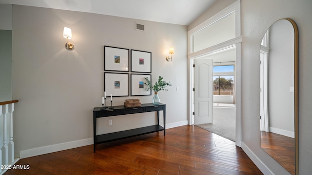 hallway featuring visible vents, baseboards, and hardwood / wood-style flooring