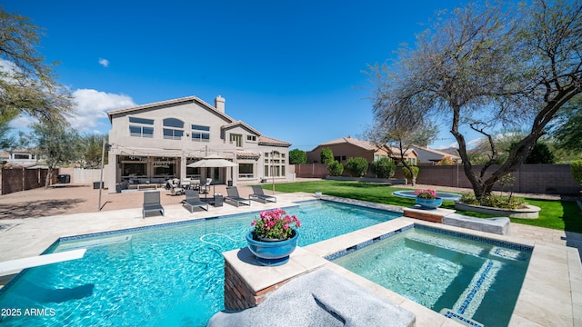 back of house featuring a fenced backyard, a fenced in pool, an in ground hot tub, a chimney, and a patio area