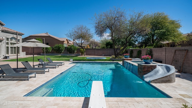 view of pool with a patio area, a pool with connected hot tub, a fenced backyard, and a diving board