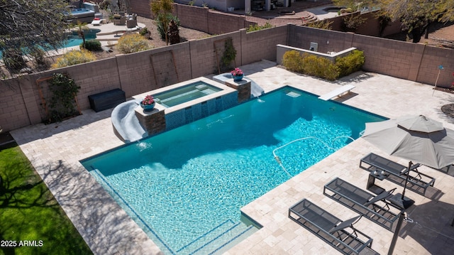 view of swimming pool featuring a fenced backyard, a pool with connected hot tub, a patio, and a diving board