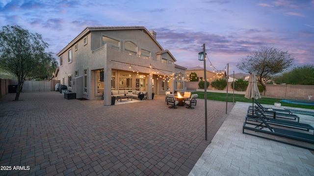 exterior space featuring stucco siding, an outdoor living space with a fire pit, a fenced backyard, and a patio area