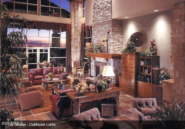 living area featuring a high ceiling, a fireplace, and stone tile flooring