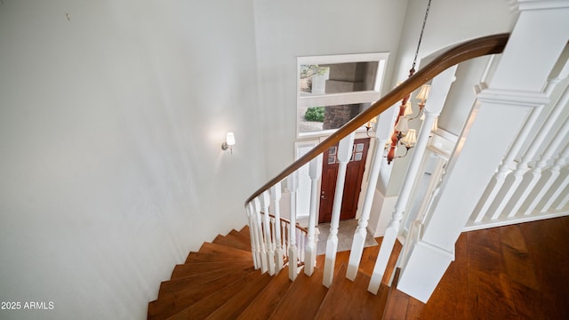 stairs with decorative columns and wood finished floors