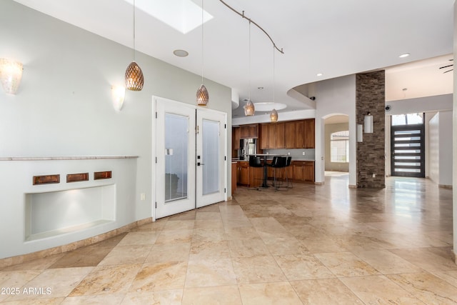 kitchen with a high ceiling, french doors, stainless steel fridge, and hanging light fixtures