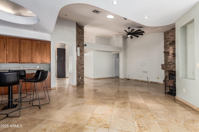 kitchen with a breakfast bar area, a high ceiling, a fireplace, and ceiling fan