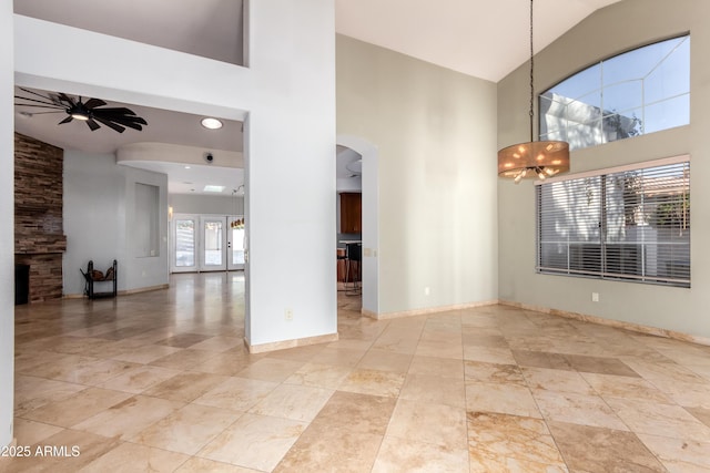 empty room with vaulted ceiling, a fireplace, french doors, and ceiling fan