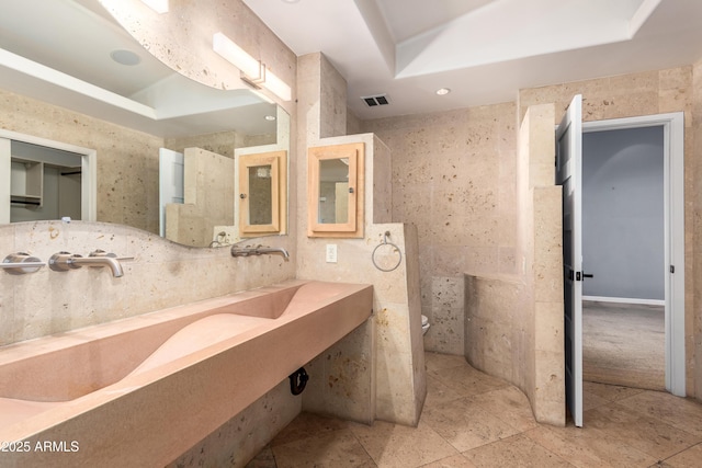 bathroom with toilet, a tray ceiling, and sink