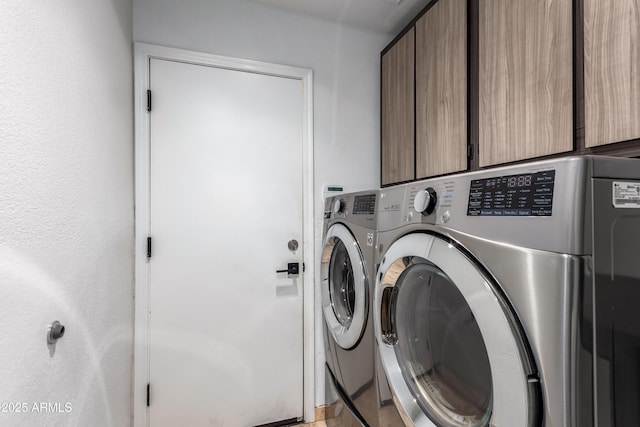 clothes washing area featuring washing machine and dryer and cabinets