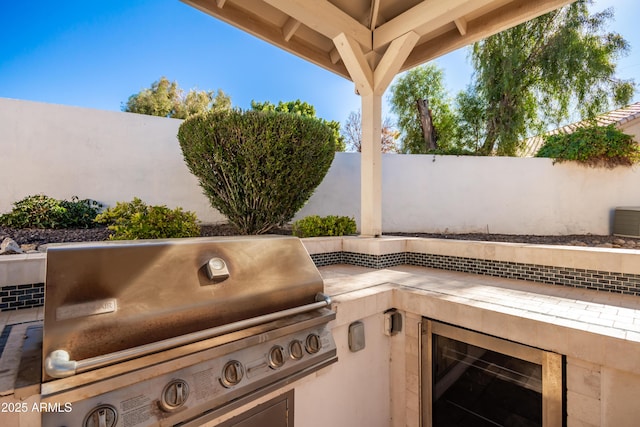 view of patio with an outdoor kitchen, wine cooler, and a grill