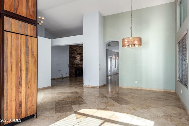 spare room with a high ceiling, a notable chandelier, and a fireplace