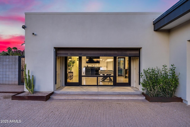 exterior entry at dusk featuring stucco siding