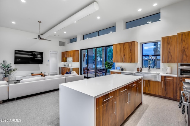 kitchen with brown cabinets, a high ceiling, a sink, light countertops, and modern cabinets