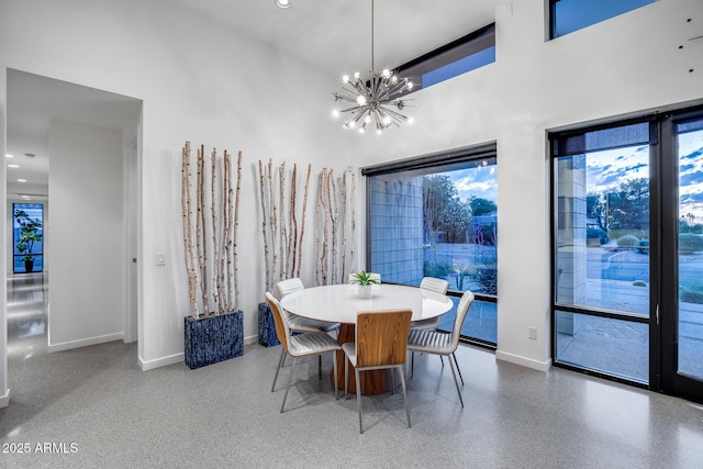 dining room featuring an inviting chandelier, baseboards, speckled floor, and a high ceiling