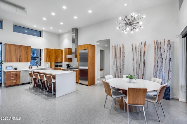 kitchen with a center island, a high ceiling, brown cabinets, and stainless steel appliances