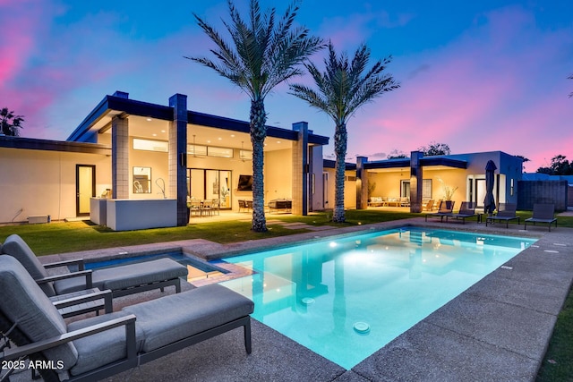 rear view of house featuring a patio, an in ground hot tub, an outdoor pool, and a lawn