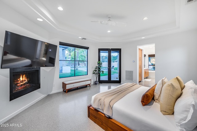 bedroom featuring a warm lit fireplace, access to exterior, recessed lighting, baseboards, and a tray ceiling