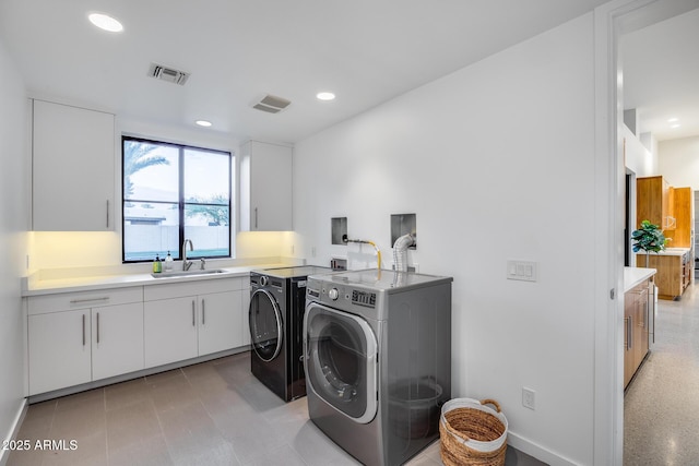 washroom featuring a sink, visible vents, cabinet space, and washer and dryer