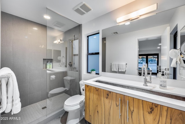 bathroom featuring toilet, visible vents, a shower stall, and vanity