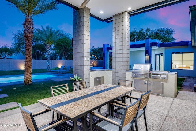 patio terrace at dusk featuring grilling area, a fenced backyard, an outdoor kitchen, a fenced in pool, and outdoor dining space