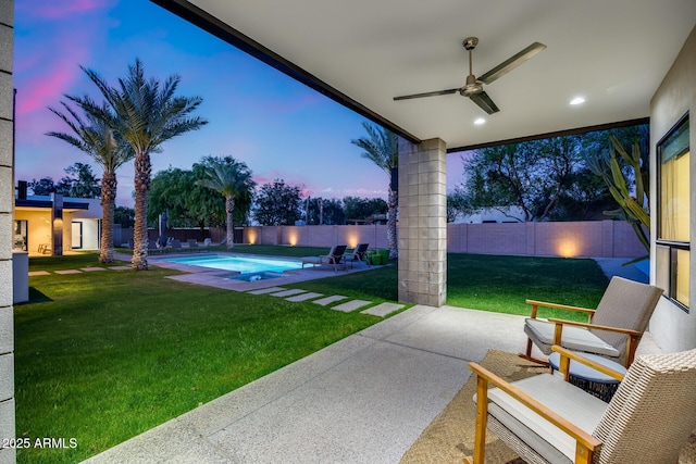 patio terrace at dusk featuring a lawn, a ceiling fan, a fenced backyard, and a fenced in pool