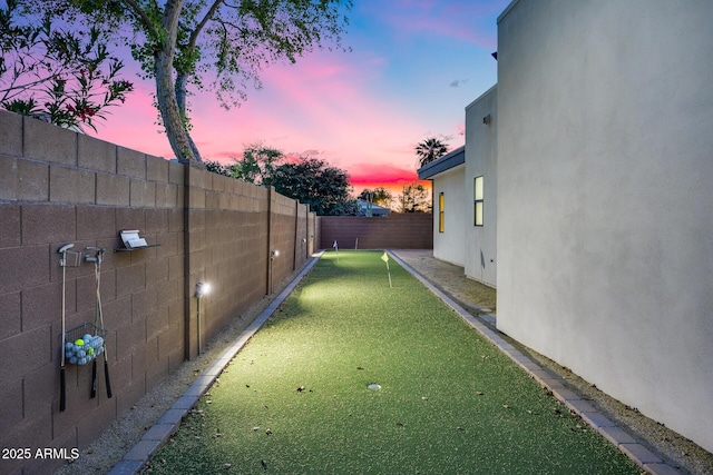 yard at dusk featuring a fenced backyard