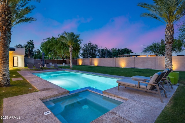 pool at dusk with a lawn, a pool with connected hot tub, a fenced backyard, and a patio area