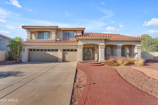 mediterranean / spanish-style home featuring a tiled roof, french doors, a garage, concrete driveway, and stucco siding