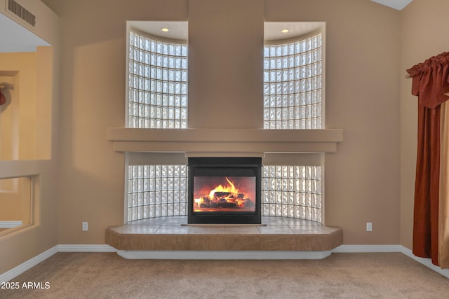 details featuring carpet floors, baseboards, visible vents, and a tiled fireplace