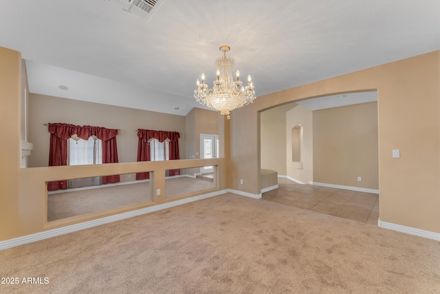 empty room with an inviting chandelier, a healthy amount of sunlight, baseboards, arched walkways, and carpet flooring