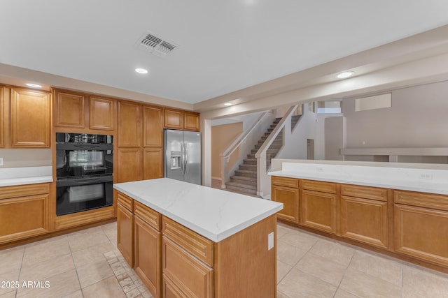 kitchen featuring dobule oven black, stainless steel refrigerator with ice dispenser, visible vents, light tile patterned floors, and light countertops