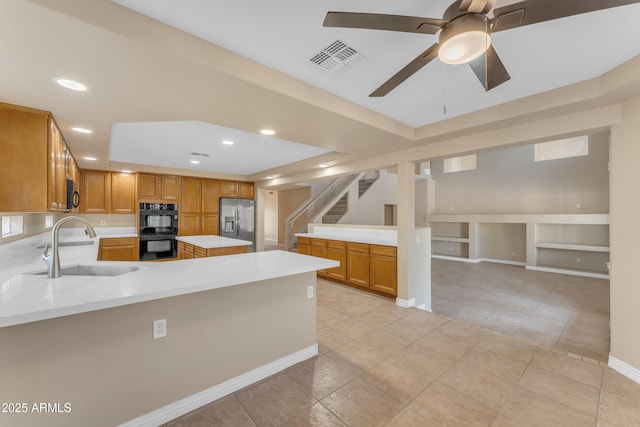 kitchen featuring dobule oven black, visible vents, a sink, light countertops, and stainless steel fridge