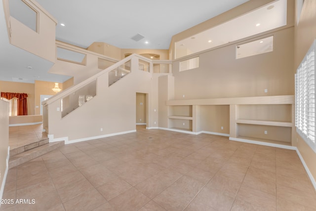 unfurnished living room with tile patterned floors, visible vents, built in features, and a towering ceiling