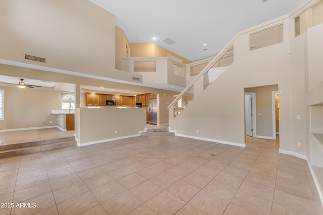 unfurnished living room featuring visible vents, a ceiling fan, a towering ceiling, and light tile patterned floors