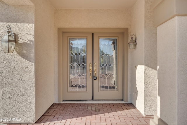 property entrance featuring stucco siding and french doors
