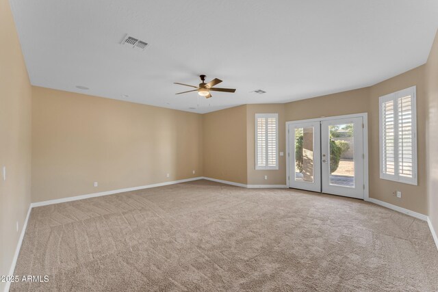 carpeted spare room featuring baseboards, ceiling fan, french doors, and visible vents