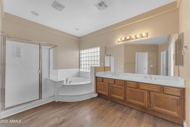 full bathroom featuring a garden tub, visible vents, a shower stall, wood finished floors, and a sink