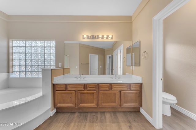 full bath featuring a sink, a garden tub, toilet, and wood finished floors