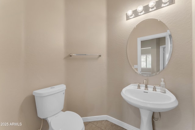 bathroom with baseboards, tile patterned floors, and toilet