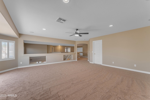 unfurnished living room featuring arched walkways, baseboards, visible vents, and carpet