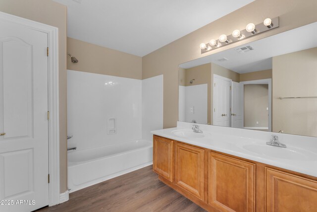 bathroom with a sink, shower / bathtub combination, wood finished floors, and visible vents